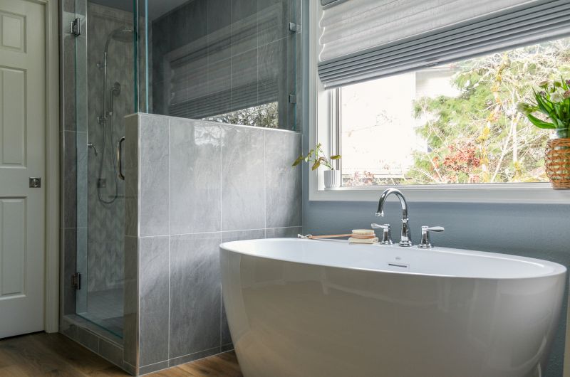 Angled photo showing gorgeous blue gray tile shower and free-standing bathtub.