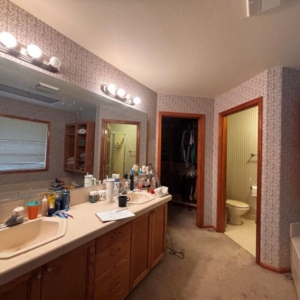 Bathroom vanity with dated finish and hollywood style vanity lights prior to remodel.