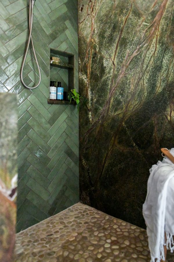 Green shower tile laid in herringbone pattern in walk-in shower.
