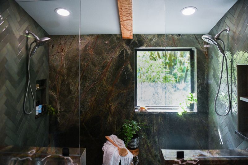 Entry to dual shower with rainforest marble walls and mosaic pebble tile.