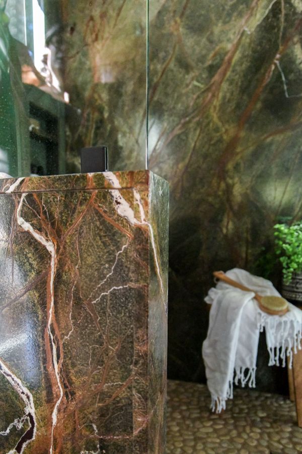 Pony wall finished with rainforest marble at the entry to large dual-shower.