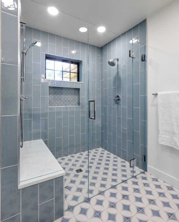 Blue tiled shower with tiled niche, window and incorporated quartz bench seat.